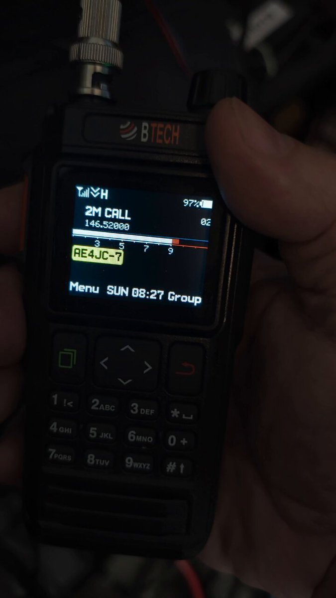 The BTECH UV-PRO handheld held in one hand, its display showing 2M CALL on 146.52000 with the callsign AE4JC-7 and a 97 percent battery