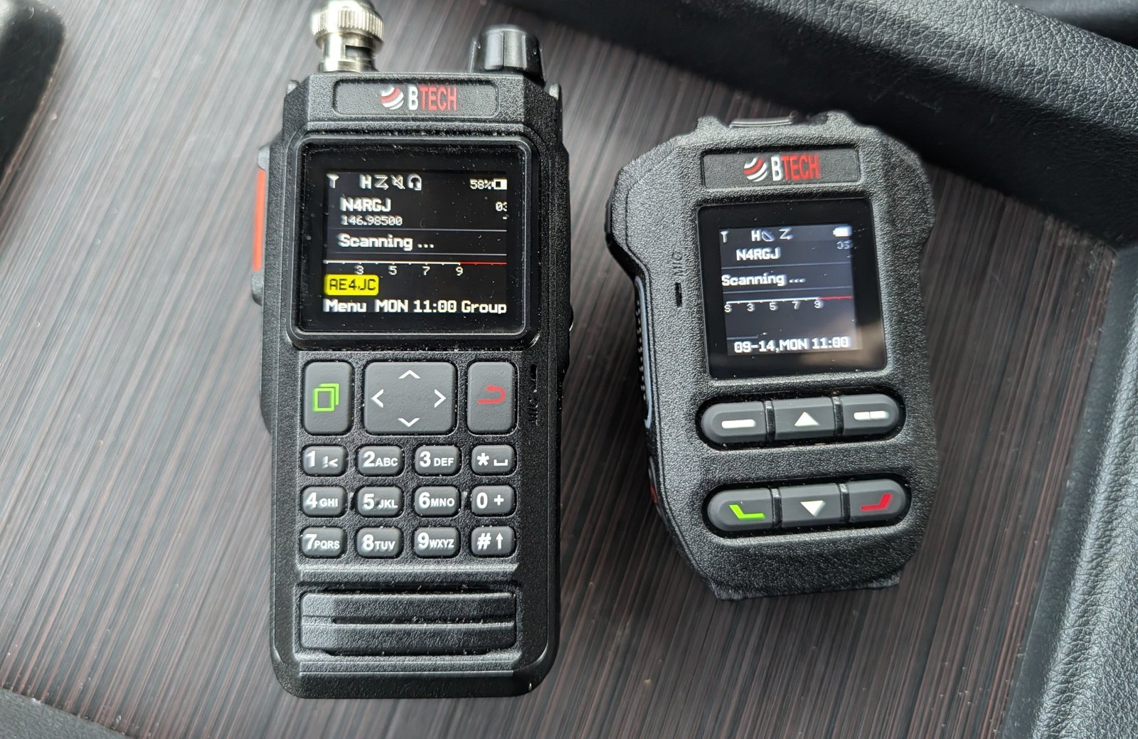 BTECH handheld radio and its BS-50 wireless speaker mic accessory sitting in a car console, both screens showing a scanning display with callsign N4RGJ